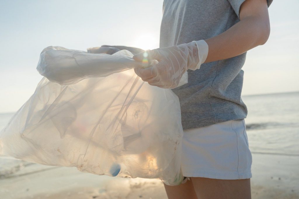 personne sur la plage faisant du tri avec un sac poubelle blanc transparent