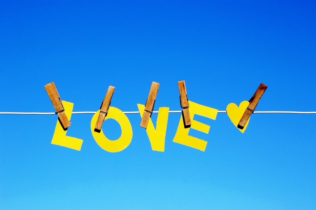 corde à linge avec des pinces à linge avec le mot love en jaune sur un ciel bleu